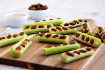 Homemade ants on a log with celery, peanut butter and raisins on a wooden board, side view....