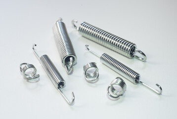 Chrome-plated metal springs on a white background. Springs for the brake system. Production of springs to order.