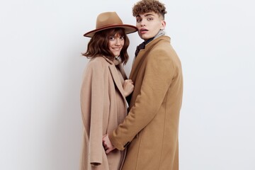 a sweet, beautiful, loving couple stands on a white background in stylish autumn clothes, gently cuddling up to each other and both look into the camera