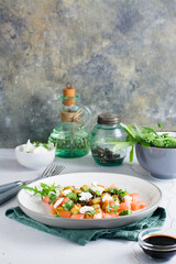 Salad of fried eggplant, tomato and feta cheese on a plate. Homemade lunch. Vertical view