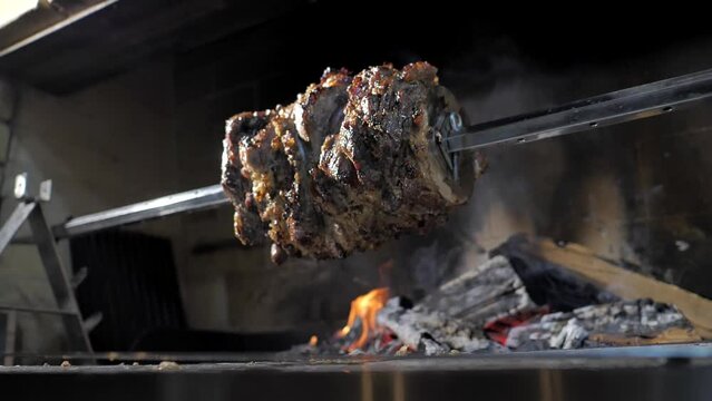 Kebab. Doner. Chef in black gloves rotates a spit of meat on coals