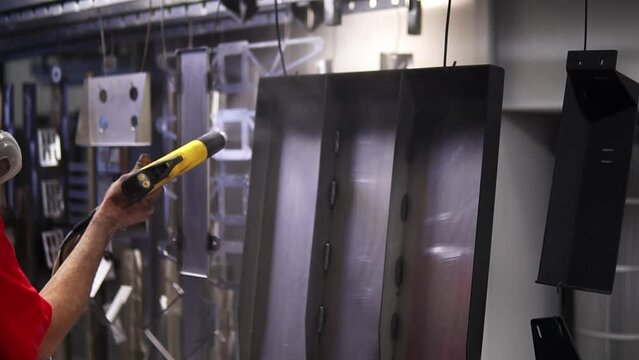 Powder coating of metal products. Employee in a protective mask with an aerosol pistol Kraskit metal parts with black color