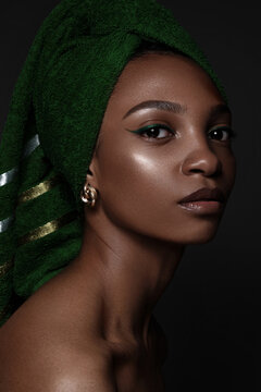 Beautiful black woman with a green towel on her head and classic make-up. Beauty face.