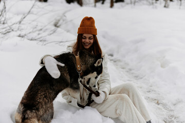 Happy young woman winter clothes walking the dog in the snow winter holidays