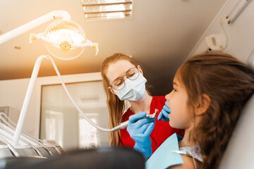 Child dentist makes professional teeth cleaning in dentistry. Professional hygiene for teeth of...