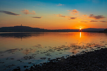 Naklejka premium Beautiful Warm Sunset During The Golden Hour On Strangford Lough, Northern Ireland With Scrabo Tower To The Left.