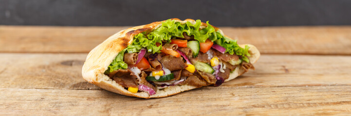 Döner Kebab Doner Kebap fast food in flatbread on a wooden board panorama with copyspace copy space