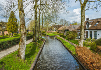 Fototapeta na wymiar A street with houses on the canal waterfront in Giethoorn village, Netherlands