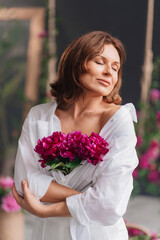 a beautiful woman with closed eyes in white clothes with a bouquet of peonies. 