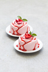 Strawberry cream pudding, Panna Cotta with sauce, in the shape of a rose, on a plate. Light grey background