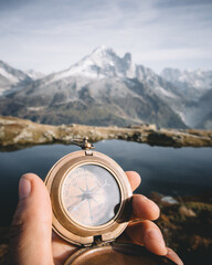 Man with compass in hand in high mountains near clear lake. Travel concept. Landscape photography