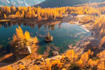 Drone flight over Federa Lake in sunrise time. Autumn mountains landscape with Lago di Federa and bright orange larches in the Dolomite Apls, Cortina D'Ampezzo, South Tyrol, Dolomites, Italy