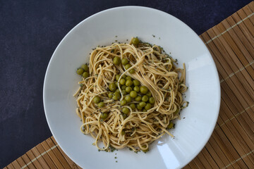 Soy noodles with peas. Vegetable protein in legumes.White plate on table with dark background.