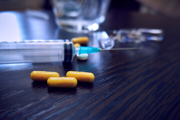Yellow pills and medical syringe. Medicine in yellow capsules on the table close-up