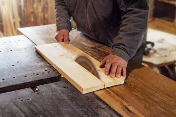 carpenter saws a wooden board with a carpentry machine.  old rustic carpentry shop. Working on woodworking machine
