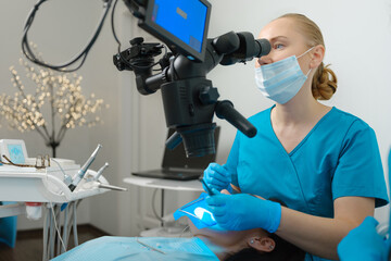 Naklejka na ściany i meble Female dentist using dental microscope