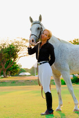  beautiful young female jockey with blond hair with a white Arabian horse.