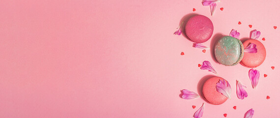 Macarons with peonies flower petals on pink background. Sweet dessert, colorful and pastel candies