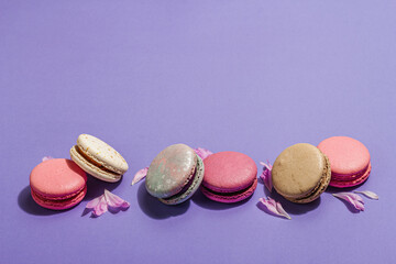 Macarons with peonies flower petals on very peri color background. Sweet dessert, pastel candy color