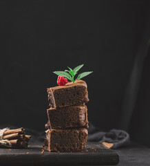 Baked pieces of chocolate brownie pie on black table, delicious dessert