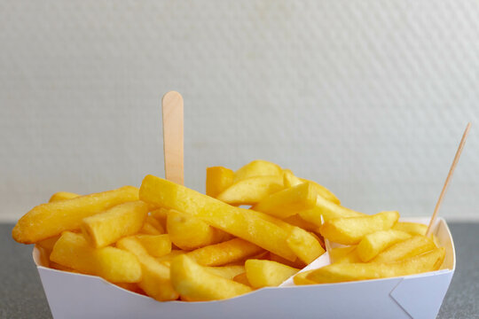 Selective focus of french fries in white paper box on table, Friet or Patat served with mayonnaise, Fritessaus or frietsaus is a Dutch accompaniment to French fries, Served popularly nationwide.