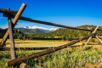 Looking through wooden fence rails at snow-capped Longs Peak in the distance, from near Estes Park,...