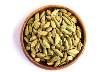 Green cardamom pods in a wooden bowl on white background.