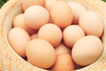 Defocus eggs in straw hat on grass background. Chicken eggs in wooden basket on green nature floor at cloudy day. Backdrop. Organic food. Springtime. Easter egg. Out of focus