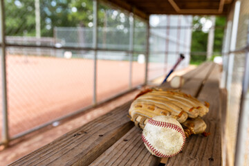 Baseball with glove on dugout bench with blurred background - obrazy, fototapety, plakaty