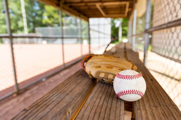 Baseball with glove on dugout bench with blurred background