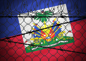 Fototapeta na wymiar Haiti flag behind barbed wire and metal fence