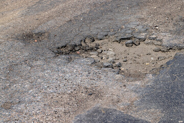 poor paved road with a lot of holes and potholes