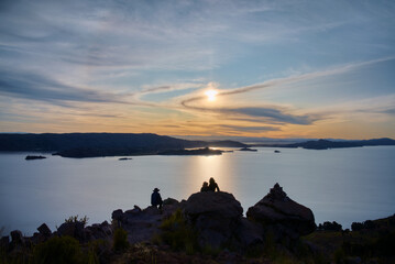 Tourists enjoy the sunset over Titicaca lake from Taquile island, Puno - Peru.