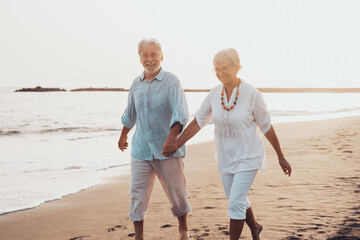 Couple of old mature people walking on the sand together and having fun on the sand of the beach...