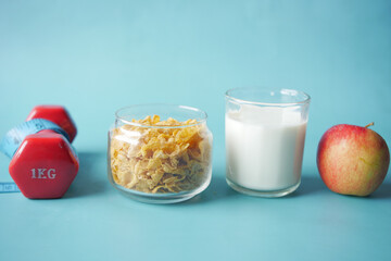 morning cereal , milk, apple and dumbbell on blue 