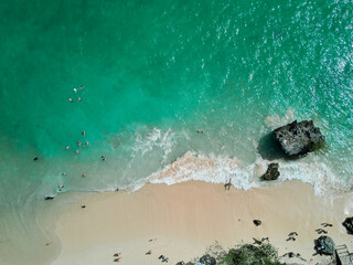 aerial drone view of padang padang beach in bali with waves, rocks and forest