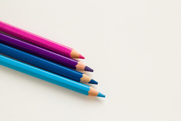 Purple, blue and pink dry crayons, on a white surface with copy space.