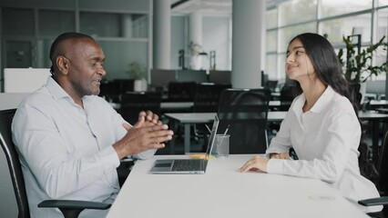 African adult 50s boss businessman recruiter banker talking to arabic female candidate young trainee handshaking client at office meeting accept common project approve cooperation teamwork partnership
