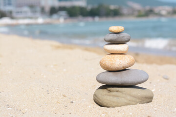 Fototapeta na wymiar Stack of stones on sandy beach near sea, space for text