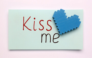 Card with phrase Kiss me and blue heart on white background, top view