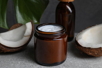 Fototapeta na wymiar Jar of hand cream and coconut pieces on grey table