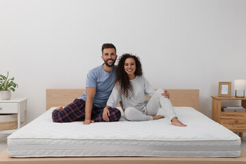 Happy couple on bed with comfortable mattress at home