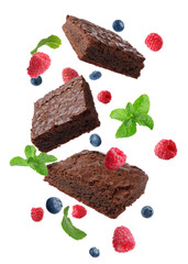 Slices of delicious chocolate brownie with fresh berries and mint flying on white background