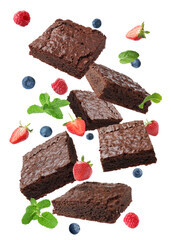 Slices of delicious chocolate brownie with fresh berries and mint flying on white background