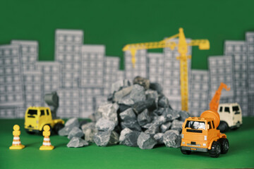 Models simulator on green background, construction vehicles toys, trucks, backhoes, and cranes work at site, transport resource materials, rock, and mortar, real estate business, and city development.