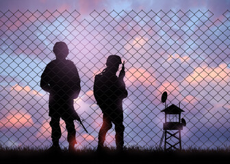 Silhouettes of border guards at post outdoors in evening