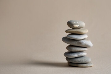 Stack of stones with drawn happy face on beige background, space for text. Be in harmony and enjoying your life