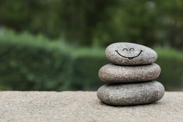 Stack of stones with drawn happy face outdoors, space for text. Be in harmony and enjoying your life