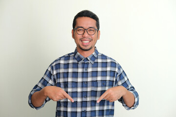 Adult Asian man smiling happy while pointing down