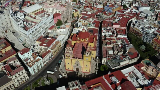 Aerial rotating shot over Taxco de Alarcon city along Santa Prisca Parish Church in Guerrero state, Mexico on a bright sunny day.
